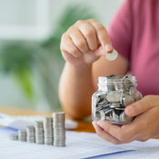 A child stacking coins from a jar onto a table.