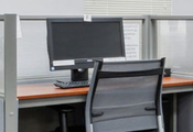 Public computer station with a computer at a desk and a chair.