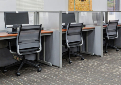Public computer station with a line of computers at a desk and chairs.