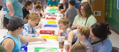 People of various ages working on a craft at an event.